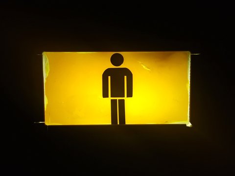 Close-up Of Illuminated Yellow Sign Against Black Background
