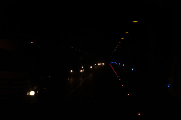 Lights from lamps and cars in the tunnel. Light from lanterns in the dark. Black background with multi-colored dots.
