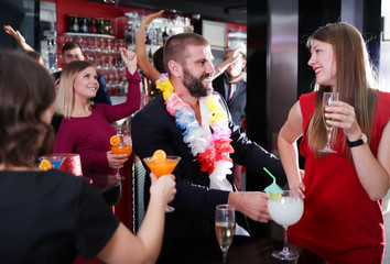 Man with female colleague on corporate party in Hawaiian style in bar