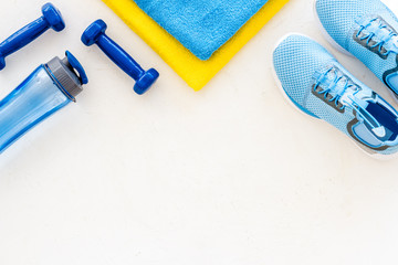 Fitness set with sneakers, dumbbells, towel on white background top view copy space