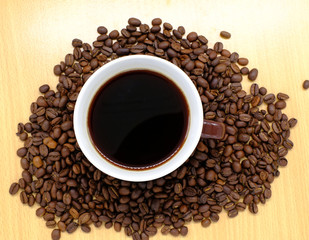 Coffee cup on wooden kitchen table. Top view with morning sunlight
