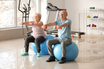 Elderly man and woman exercising in gym