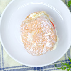 German Berliner doughnut with raspberry jam filling on background. Macro image of a donut with jam. Homemade dessert. Famous sweets.
