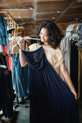 beautiful asian woman looking at some clothes in the fashion store. shopping concept