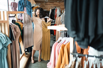 beautiful asian woman looking at some clothes in the fashion store. shopping concept