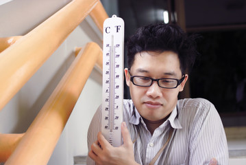 Sick and tired Asian man with thermometer suffering cold and flu virus.
