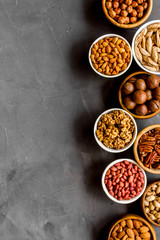 Nuts set in bowls on grey background top-down frame copy space