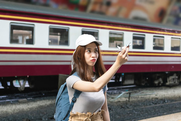 Happy young Asian lady tourist with model airplane at train station. Travel lifestyle concept.