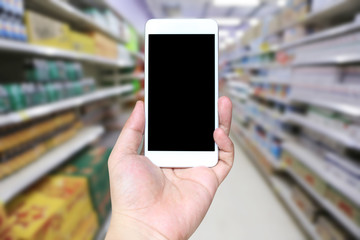 Hand of a man holding smartphone device in the Shopping mall background.