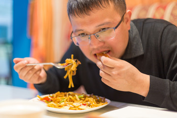 Man eating noodles in a cafe during lunch