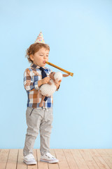 Cute little boy with party decor and toy near color wall