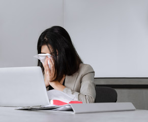 Sick business woman sneezing while working in meeting room. Working and seasonal inflection concept.