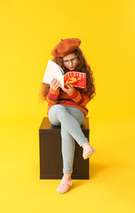 Cute little girl with magazine on color background