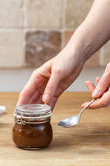 Female hands holding a vegan raw jam on a wooden table. Plum, apricot and raspberry jam. Vegan food on a table.