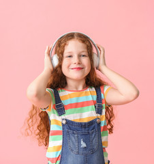 Cute little girl listening to music on color background
