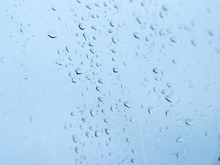 Raindrops on the window glass against the blue sky closeup.