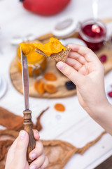 Child hand holding a vegan bread with raw apricot jam making a breakfast for himself. Young hands preparing food with blurred background.