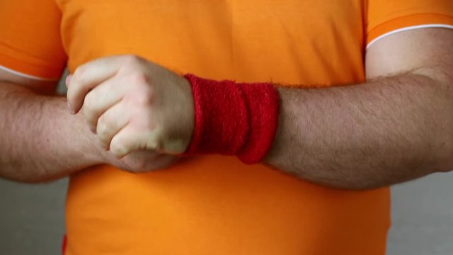 closeup man puting two cotton wristbands on the hands. preventive protection of wrist and a small towel to wipe sweat