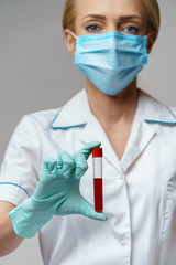 medical doctor nurse woman wearing protective mask and gloves - holding virus blood test