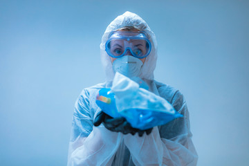 Medical doctor, scientist in full body suit for prevention from viruses and diseases holding a antiseptic tissue for disinfection.