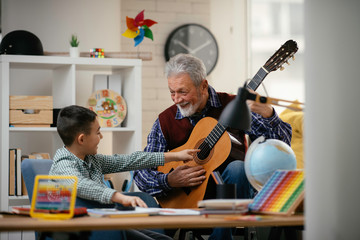 Grandpa and grandson playing guitar. Grandfather and grandson enjoying at home.	
