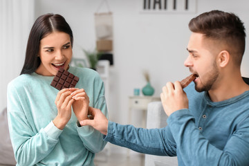 Emotional young couple eating chocolate at home