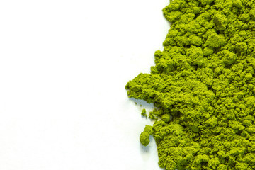 Powdered green matcha tea on a white isolated background close-up. Texture of matcha tea macro background. Copy space. Top view. Flat lay.