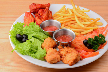 Close up gourmet main dish for dinner with crispy fried chicken, french fries and veggies on white plate.
