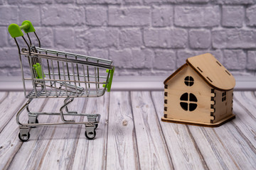 Shopping cart with green handle and wooden house on the table