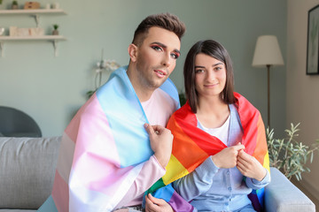 Portrait of young transgender couple with flags at home