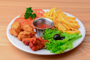 Close up gourmet main dish for dinner with crispy fried chicken, french fries and veggies on white plate.