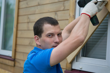Fototapeta premium a worker in a blue uniform, drills the Windows of the house from thieves when moving to another address