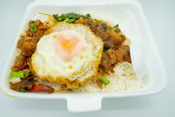 Crispy pork with basil and fried egg in a box