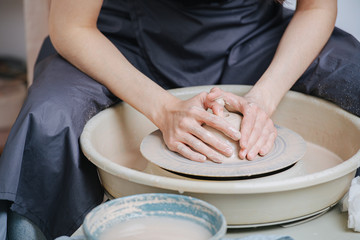 Woman hands working with caly on a pottery wheel for a future vase