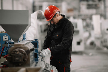 Portrait of worker in factory. Young handsome man working in factory.	