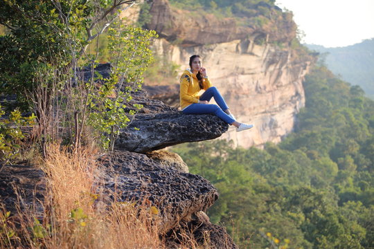 Woman sitting on the cliff at Pha Tam National Park, Ubon Ratchathani, Thailand.