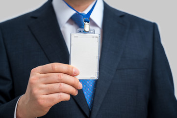 Businessman in suit wearing a blank ID tag or name card on a lanyard at an exhibition or conference.