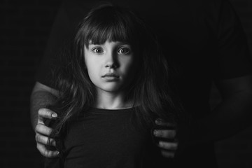 Father with his scared little daughter on dark background. Concept of domestic violence