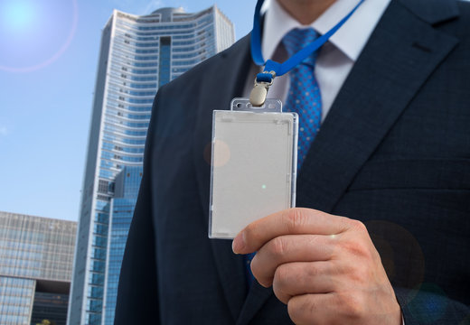 Businessman in suit wearing a blank ID tag or name card on a lanyard at an exhibition or conference.
