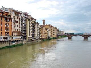 Fototapeta na wymiar Landscape from the bridge on the Arno River surrounded by ancient Florence houses on a background of cloudy evening sky.