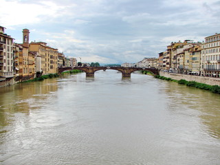Obraz premium Landscape from the bridge on the Arno River surrounded by ancient Florence houses on a background of cloudy evening sky.