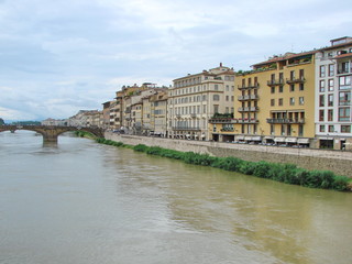 Obraz premium Landscape from the bridge on the Arno River surrounded by ancient Florence houses on a background of cloudy evening sky.