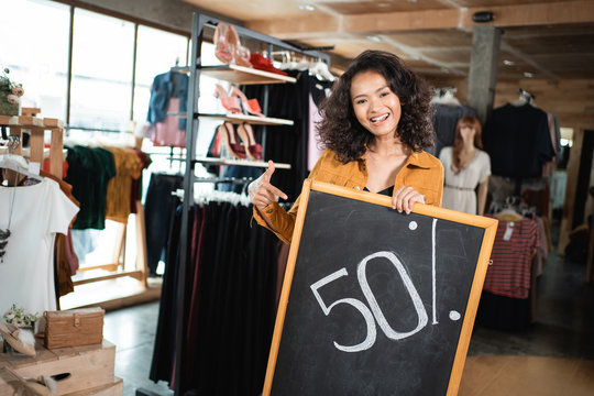 attractive young business owner holding chalkboard with 50 percent discout on the board