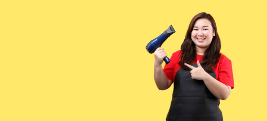 Hairdresser drying hair in a beauty salon isolated on yellow background in studio With copy space.