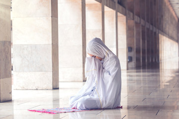 Young muslim woman praying in the mosque