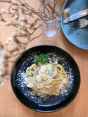 Cheese and Creamy Fettuccine Carbonara on Top View on Table, Decorate with Dried Flower in Glass Bottle 