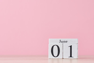 Wooden block calendar with date June 1 and succulent plant in the pot on pink background