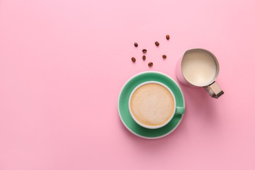 Cup of tasty cappuccino and jug of milk on color background