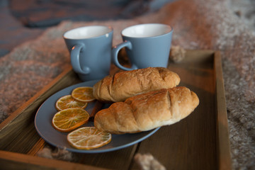 two croissants on a tray with tea