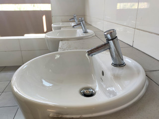 Fototapeta premium Hand washbasins at the public toilet. Installation complete with face mirror. Made from white glazed ceramic. 